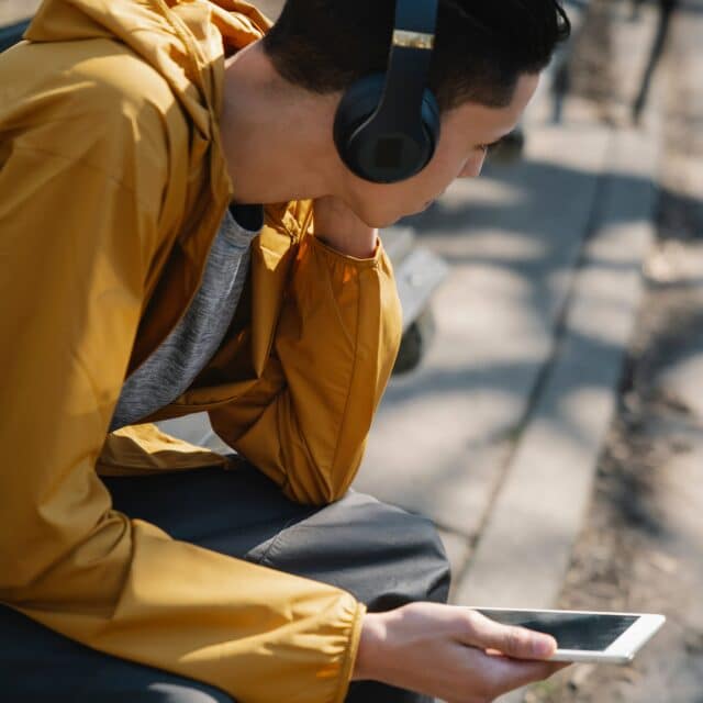 Clinical Psychologist: A boy with a bun and headphones on has a telehealth psychology session on his phone outside
