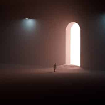 A small figure walking through a large lit archway