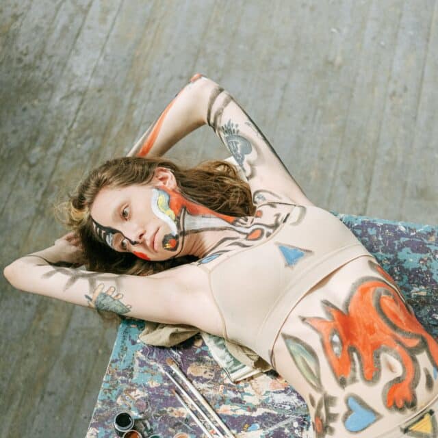 Body Dysmorphia: A girl covered in paint lays back on a canvas