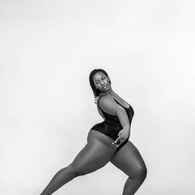 A BIPOC woman holds a ballet pose