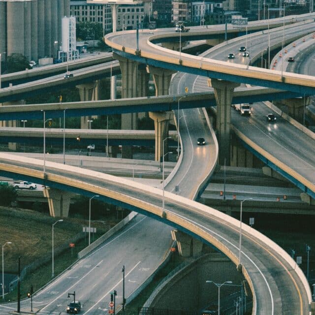 A darker image of overlapping roads leading to multiple routes. The city scape can be seen in the back.