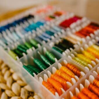 An organised plastic box on a table with an assortment of coloured thread.