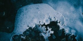 A dark blue and white image of abstract ice with swirls and ice particles