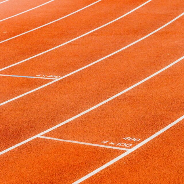 An image of a running track as it bends around a curve. It is a bright orange colour.